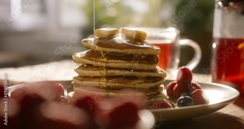 Stack of delicious neat pancakes with pieces of butter drizzled with honey or maple syrup. No people, advertising cinematic. Mouthwatering breakfast spread of savory pancakes topped with berries