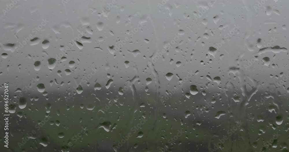 A color video of raindrops on a window, with a green field and trees in the background. pano A color video of raindrops on a window, with a green field and trees in the background. pano
