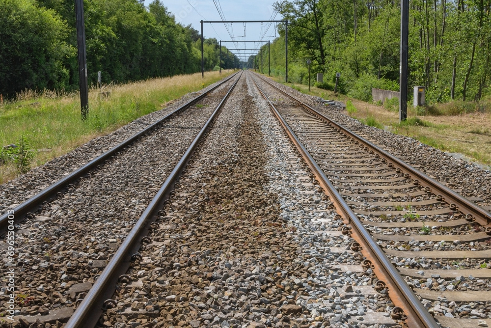 Naklejka premium Suburban railway with electric structure and wires perspective sunny day blue sky background