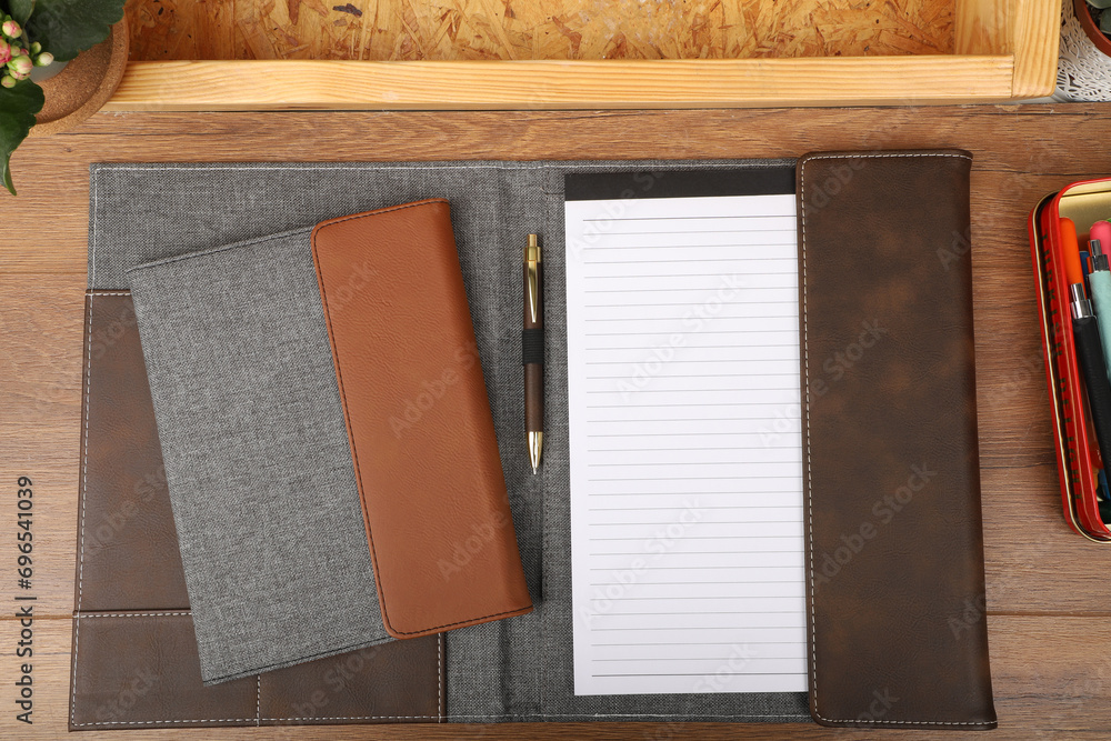Fototapeta premium Leather and fabric flap portfolio. Concept shot, top view, flap portfolio in different colors and leather pen. Custom background flap portfolio view. Flap portfolio and accessories.
