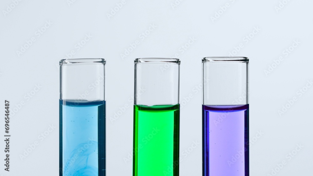 Concept of science and biotechnology. Laboratory glassware on white background. Test tubes filled with blue, green and purple liquid. Close up. Concept of science and biotechnology. Laboratory glassware on white background. Test tubes filled with blue, green and purple liquid. Close up.