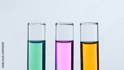 Concept of science and biotechnology. Laboratory glassware on white background. Test tubes filled with pink, green and yellow liquid. Close up.
