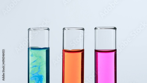 Concept of science and biotechnology. Laboratory glassware on white background. Test tubes filled with pink, green and red liquid. Close up.