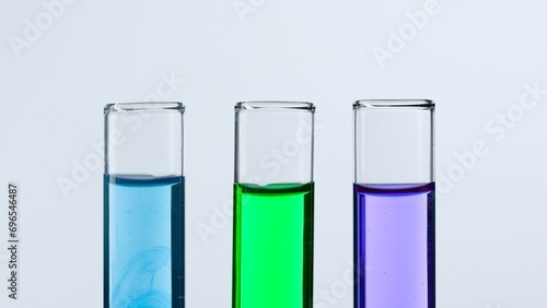 Concept of science and biotechnology. Laboratory glassware on white background. Test tubes filled with blue, green and purple liquid. Close up.