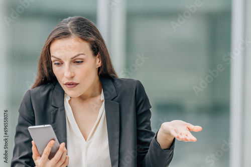 business woman with mobile phone and expression of incomprehension or resignation photo