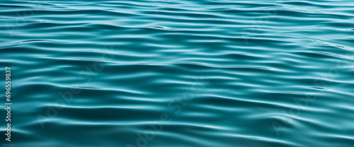 Azure aqua water with gentle ripples and reflections. Subtle waves across a deep turquoise backdrop. Ideal for design layouts on web banners and website headers.