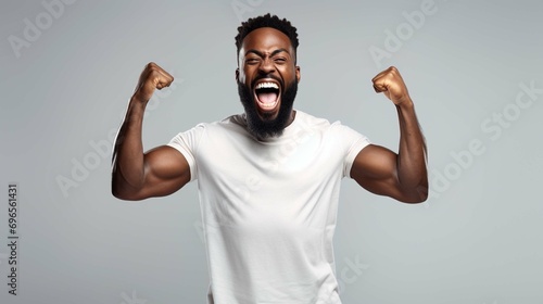 Happy thrilled dark skinned man with small beard clenching fists celebrating success enjoying victory keeps eyes closed shows even teeth isolated over white background. photo