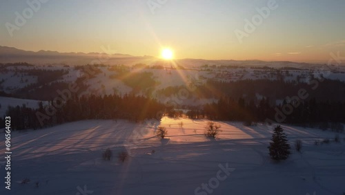 Przelot nad szczytem góry na Podhalu zimą z zachodem słońca w tle - 4K photo