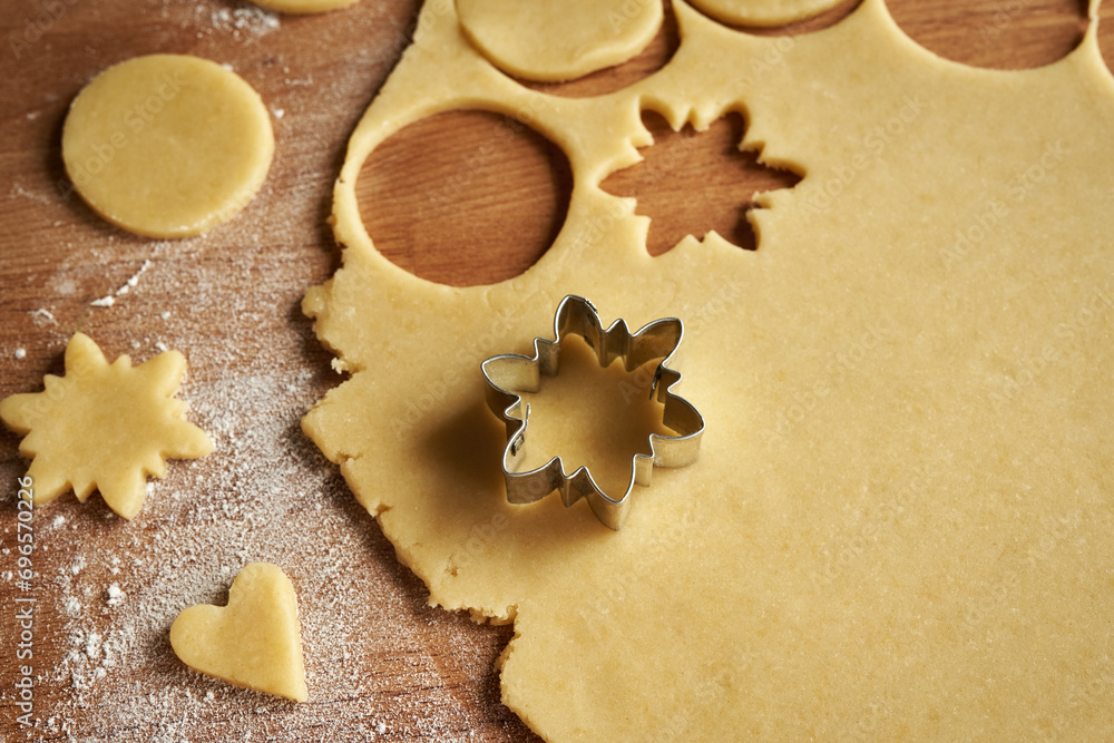 Cutting out star shapes from raw pastry dough to prepare homemade Linzer Christmas cookies