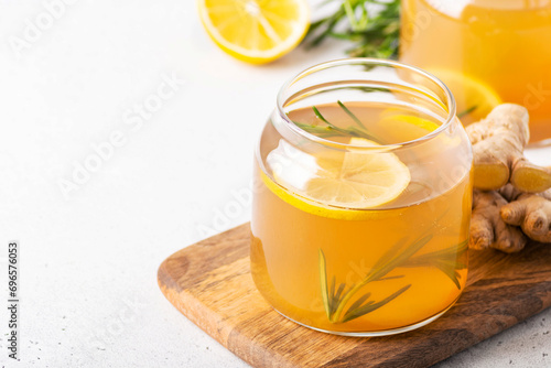 Kombucha with ginger in a jar on a light background, decorated with rosemary, copy space