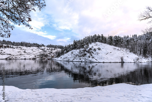 winter landscape. Forest and hill reflected in cold lake