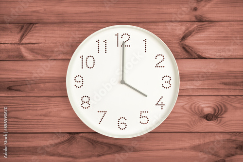 Four o'clock. Time management or business concept. Plain white wall clock showing 4 pm on a wooden background. Copy space. Opening or closing hours. Schedule or working, study hours.