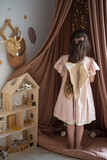 girl with wings plays with a doll house