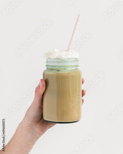 Woman holding coffee in mason jar glass with whipped cream on top