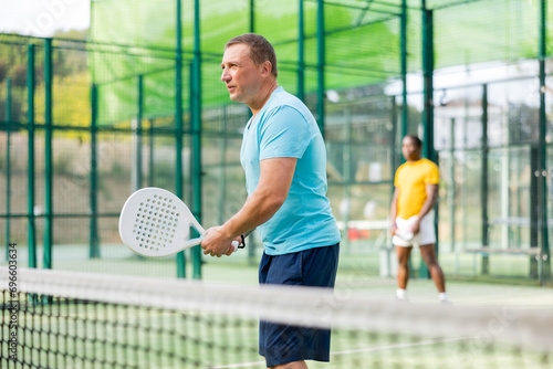 Active european man tennis player with a padel racket training on an outdoor court