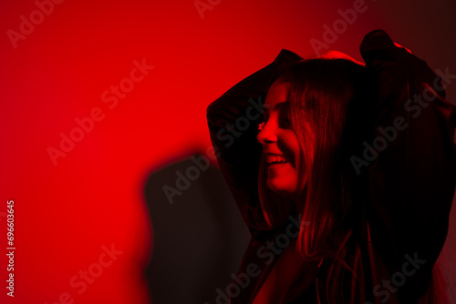 Beautiful young model wearing black clothes, with his hand on his head making poses for the bright picture of red.