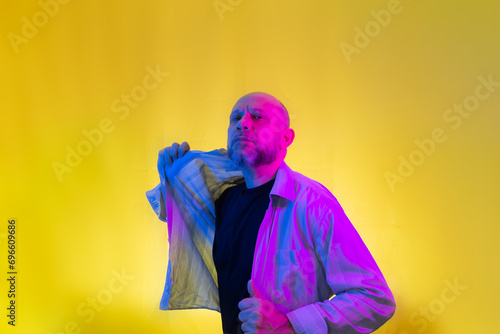 Bearded, bald man opening his shirt.