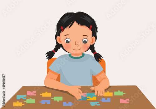 Cute little girl playing colorful puzzle at the table