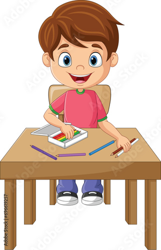Cartoon little boy with pencils on the desk