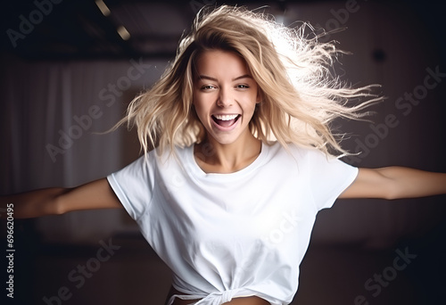 Joyful young blond woman having fun, dancing with happy smiling face and relaxed emotion