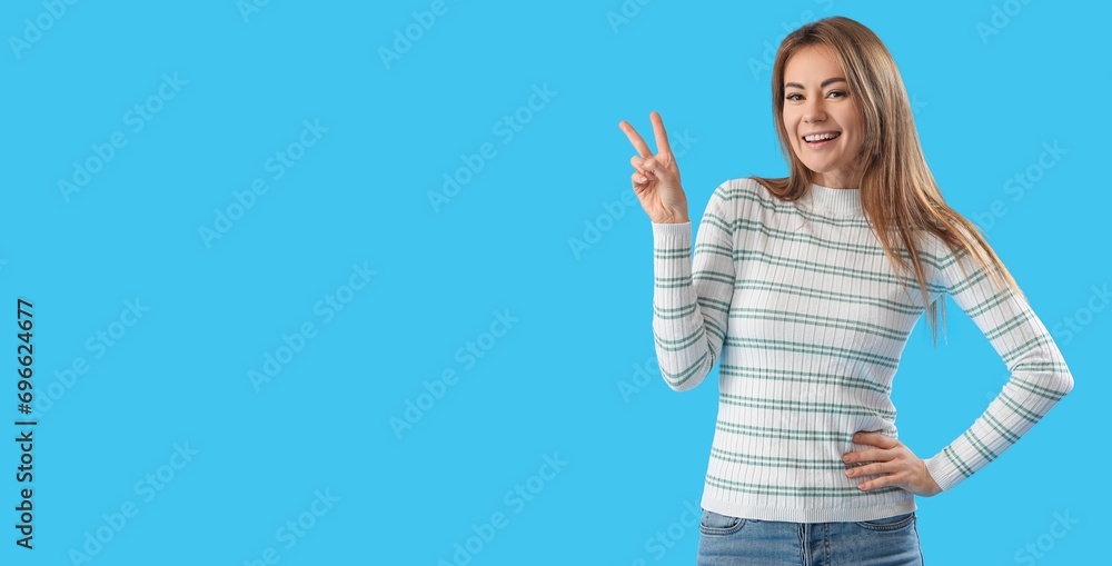 Young woman showing victory gesture on blue background with space for text Young woman showing victory gesture on blue background with space for text