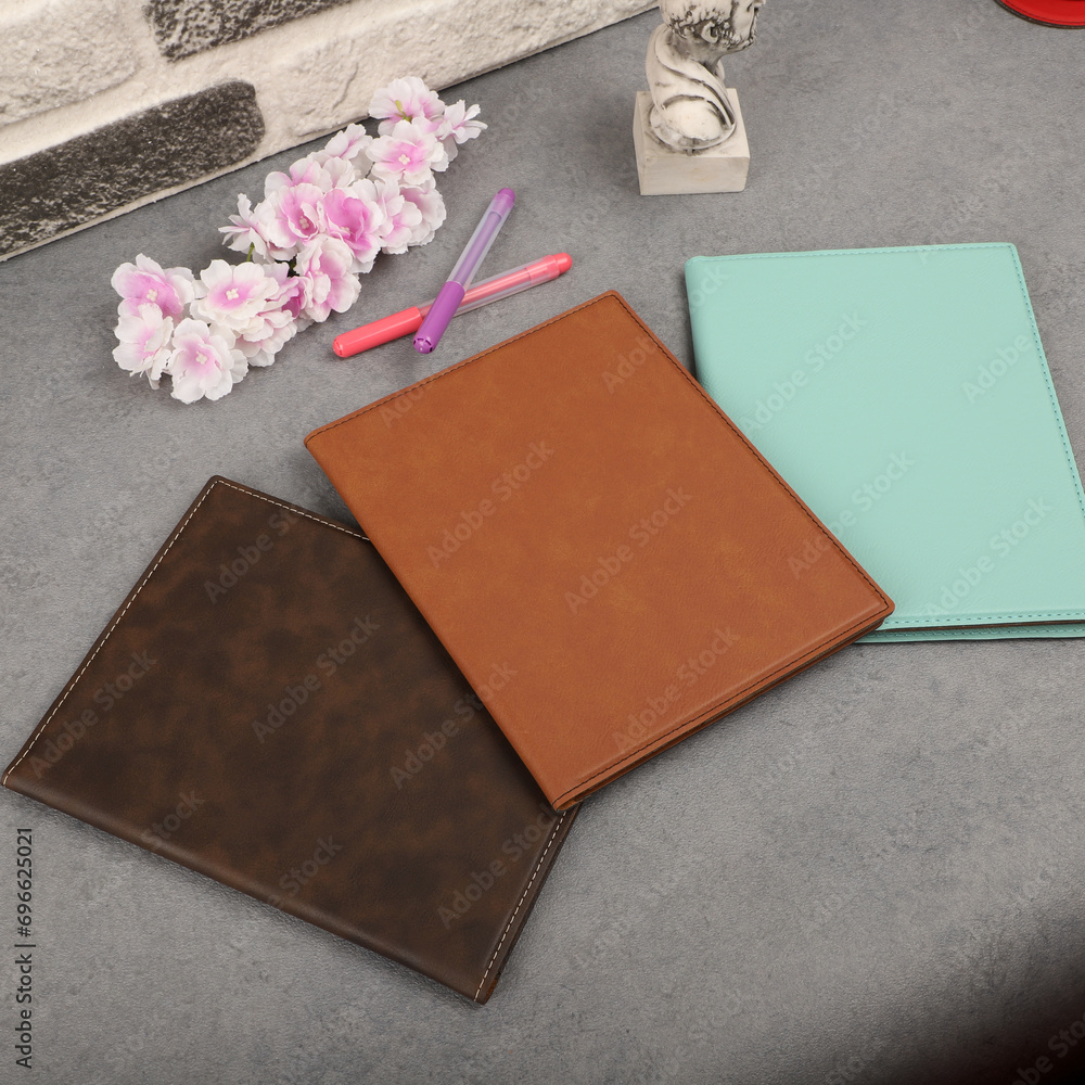 Fototapeta premium Leather portfolio. Concept shot, top view, portfolio in different colors and leather pen. Custom background flap portfolio view. Portfolio and accessories.