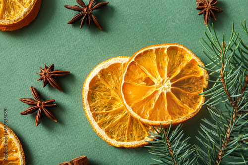 Dried orange slices with fir branch and star anise on green background
