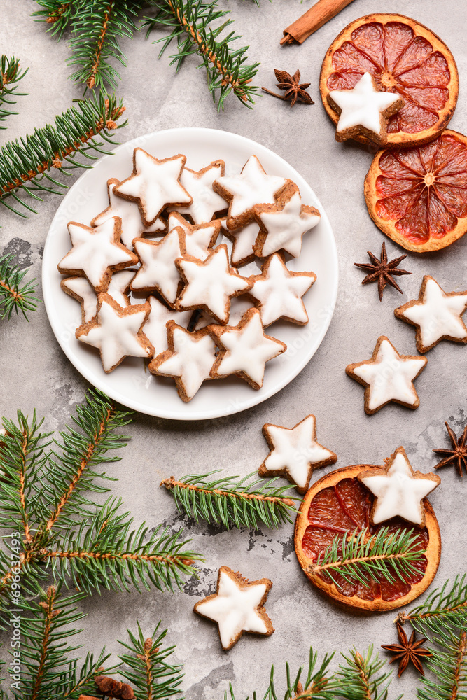 Delicious stars shaped Christmas cookies with fir branches and orange dried pieces on grey grunge background