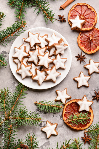 Delicious stars shaped Christmas cookies with fir branches and orange dried pieces on grey grunge background