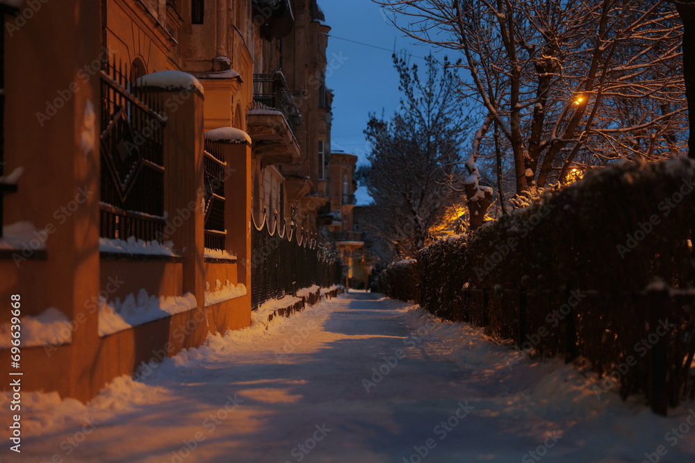 Picturesque view of city street covered with snow in evening Picturesque view of city street covered with snow in evening