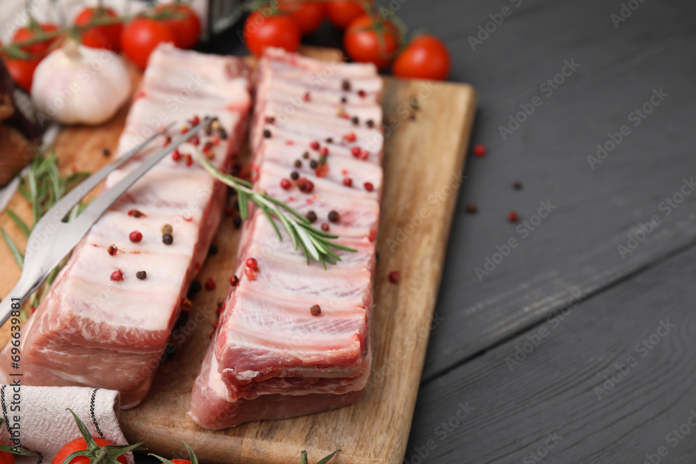 Raw pork ribs with peppercorns and rosemary on grey wooden table. Space for text Raw pork ribs with peppercorns and rosemary on grey wooden table. Space for text