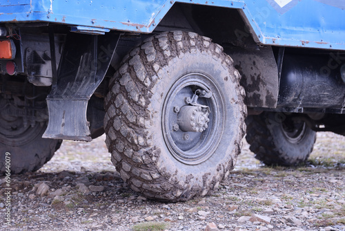 Wheel closeup in a countryside landscape with a mud road. Off-road 4x4 suv automobile with ditry body after drive in muddy road area photo