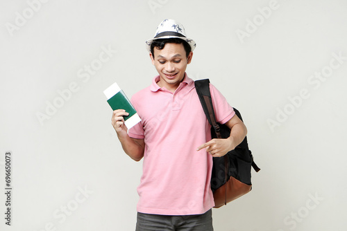 Asian man backpacker holding passport and airline ticket. pointing finger. digital nomad and travelling concept. on isolated background