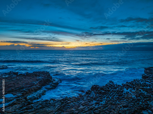 Sunrise over the sea and rock platform with high cloud