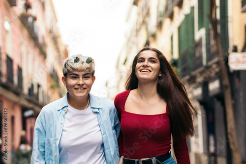 two teenager girls walking and smiling on a street. front view