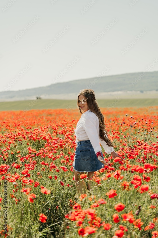 Happy woman in a poppy field in a white shirt and denim skirt with a wreath of poppies on her head posing and enjoying the poppy field. Happy woman in a poppy field in a white shirt and denim skirt with a wreath of poppies on her head posing and enjoying the poppy field.