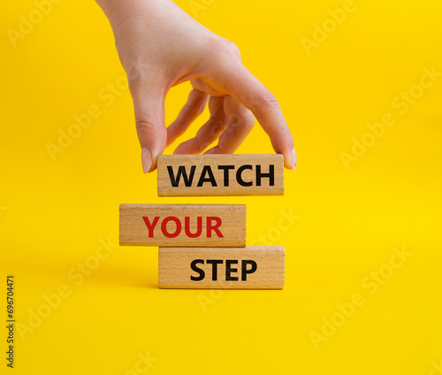 Watch your Step symbol. Concept words Watch your Step on wooden blocks. Businessman hand. Beautiful yellow background. Business and Watch your Step concept. Copy space. photo