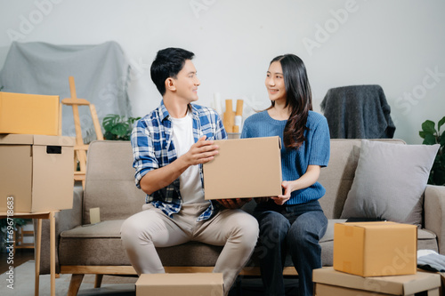 Happy asian young attractive couple man and woman with big boxes moving into a new house, new apartment for couple the new home, Moving house. on sofa.