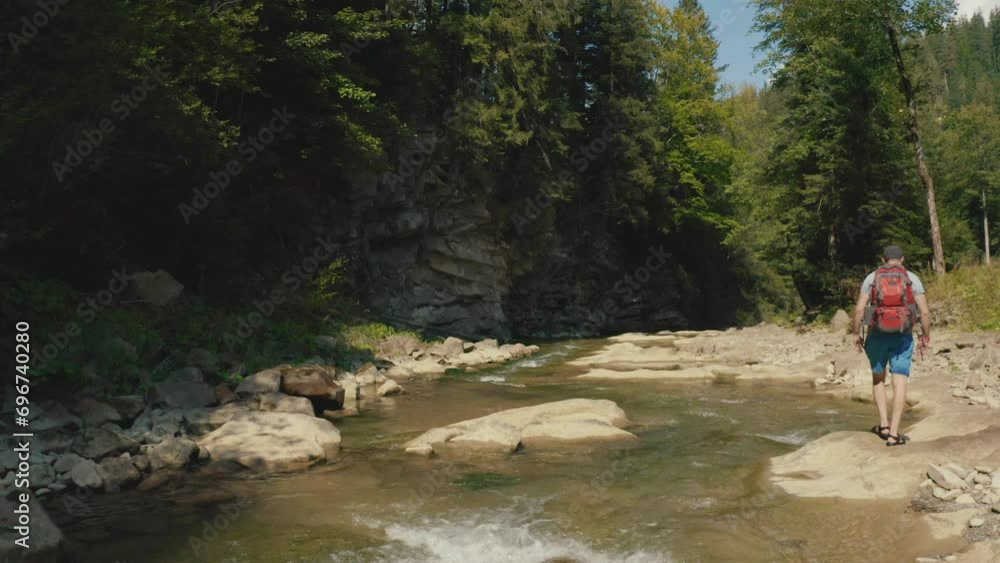 Aerial view of a man walking along a river in a mountain canyon. Single tourist hike along a mountain river Aerial view of a man walking along a river in a mountain canyon. Single tourist hike along a mountain river