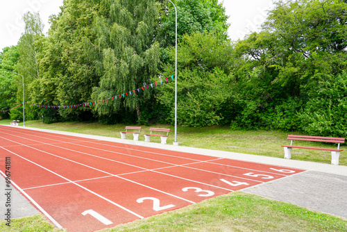 A school stadium running track with a red surface and six numbered lanes, athlete track © Zigmunds