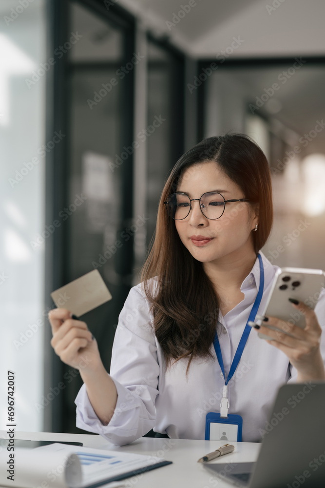 Business woman hand holding credit card and use laptop and smartphone in office. Business woman hand holding credit card and use laptop and smartphone in office.