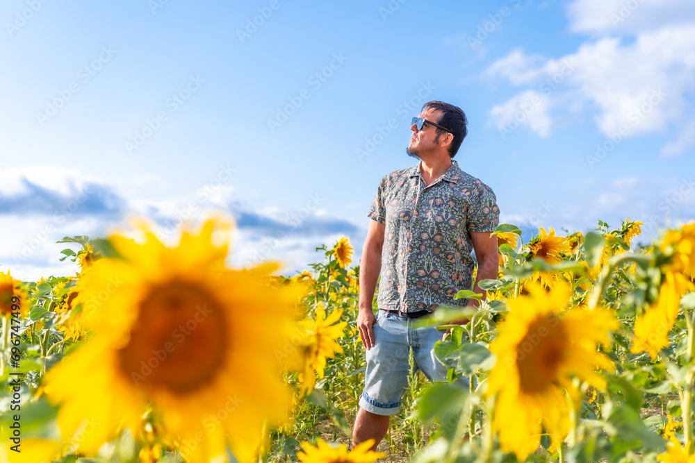 Man with sunglasses among sunflowers in summer