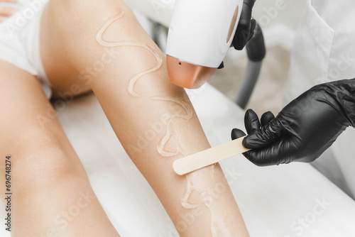 beautician applies gel for laser hair removal on smooth female legs. close-up. laser hair removal in the salon photo