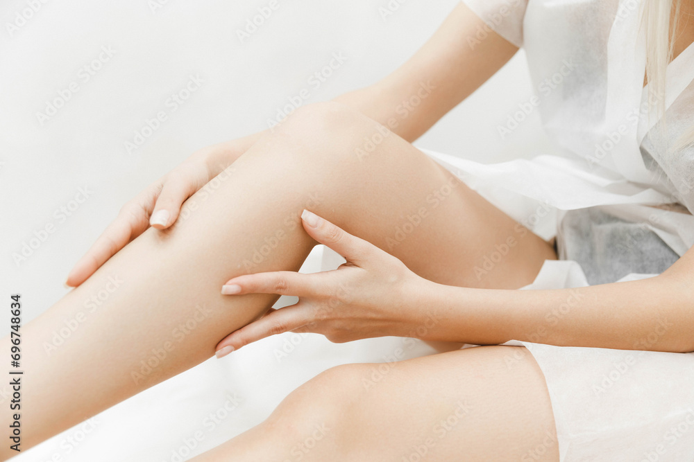 a young woman lies with her eyes closed and raises her hand up during the laser hair removal procedure. laser hair removal of the whole body. a young woman lies with her eyes closed and raises her hand up during the laser hair removal procedure. laser hair removal of the whole body.