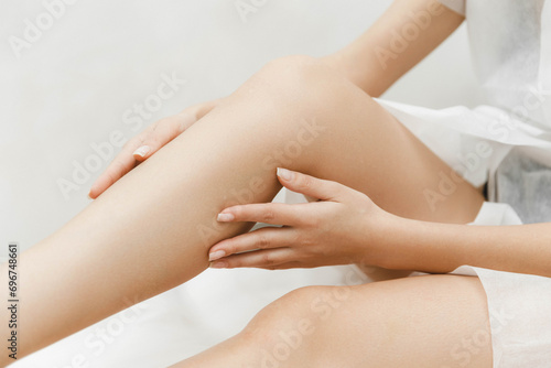 a young woman lies with her eyes closed and raises her hand up during the laser hair removal procedure. laser hair removal of the whole body.