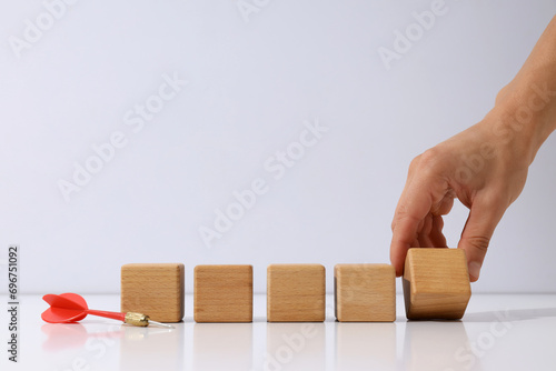 Dart, five wooden cubes and hand on light background, space for text