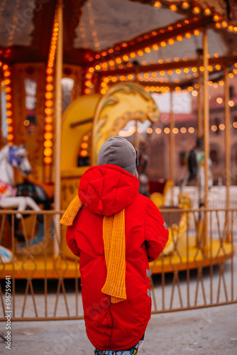 boy in red looking at the christmas carousel