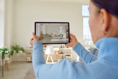 Woman takes photograph of large renovated home interior. Property owner or estate agent uses wide angle camera on smart tablet to take photo or give walkthrough video tour about new apartment for sale photo