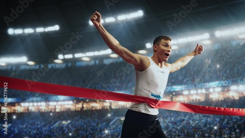 Strong Athlete is Performing at His Limit, Finishing a Competitive Run, Crossing the Finish Line with a Red Ribbon. Cinematic Sports Footage at a Crowded Arena with Spectators. Super Slow Motion photo