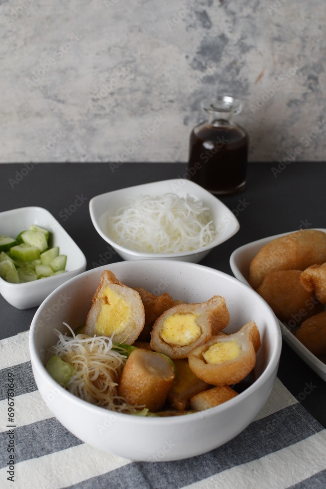 Pempek on white plate with vermicelli and cuko sauce. Pempek, mpek-mpek or empek-empek is a savory Indonesian fishcake delicacy, made of fish and tapioca, from Palembang, South Sumatera, Indonesia. Pempek on white plate with vermicelli and cuko sauce. Pempek, mpek-mpek or empek-empek is a savory Indonesian fishcake delicacy, made of fish and tapioca, from Palembang, South Sumatera, Indonesia.